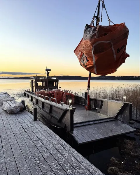 Bigbag med byggavfall lyfts ombord vid solnedgång
