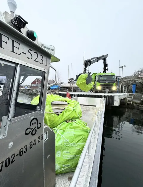 Gröna säckar med trädgårdsavfall lastas av med kran