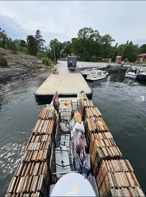 Arbetsbåten BOB vid brygga med lastpallar