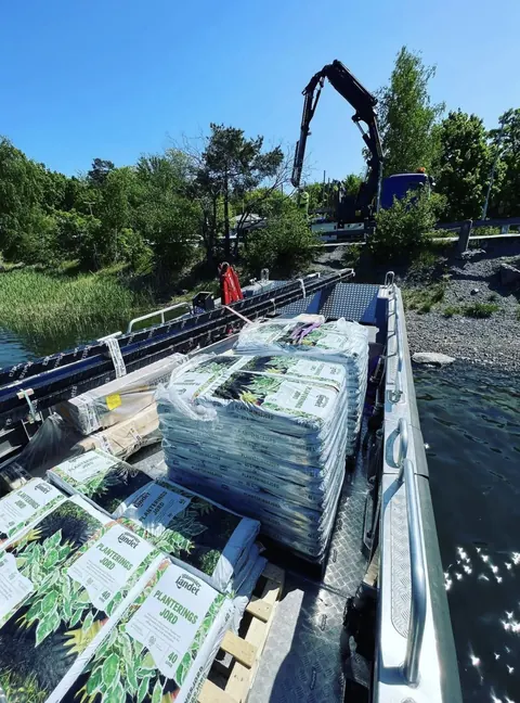 Jordsäckar lastas ombord med kranbil vid brygga